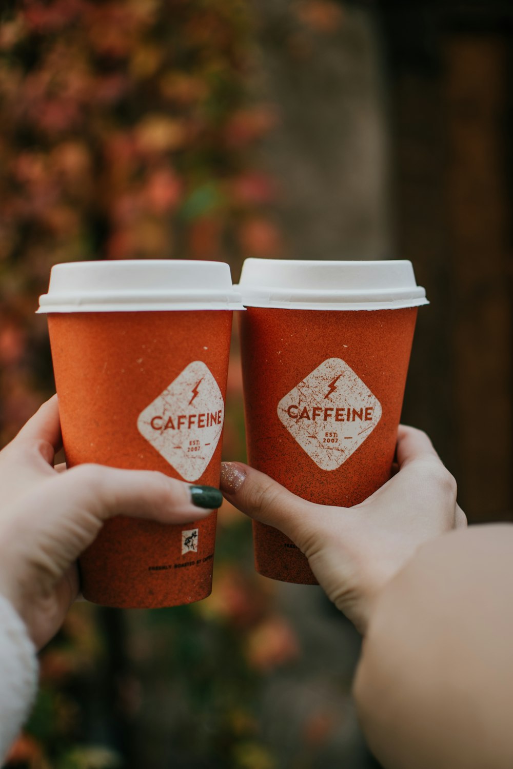 a pair of hands holding two cups of coffee