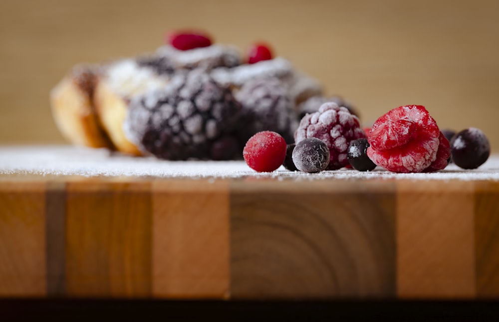 a wooden cutting board topped with berries and powdered sugar