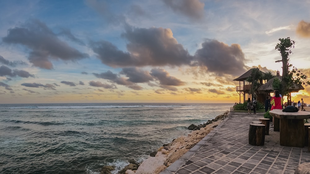 a couple of benches sitting on top of a pier next to the ocean