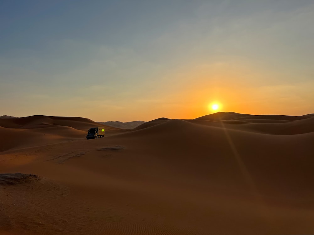 a truck driving through the desert at sunset