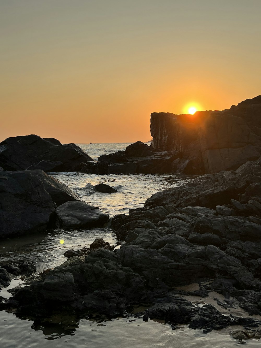 Le soleil se couche sur l’eau et les rochers