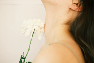 A serene close-up of a woman gently holding a delicate flower, symbolizing care and intimacy.