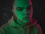Close-up of a black hoodie with neon green accents under moody lighting.