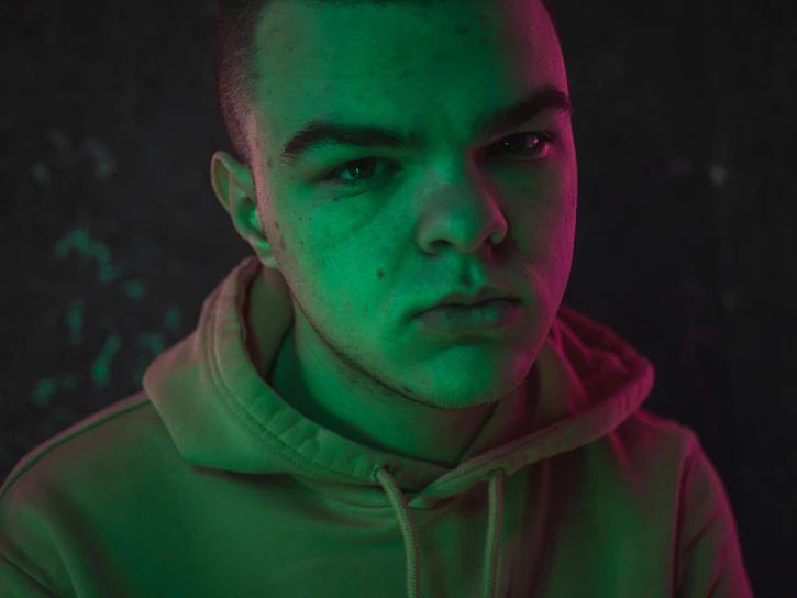 Close-up of a sleek black streetwear hoodie with vibrant fuchsia graphic design glowing under cinematic lighting.