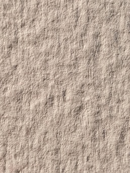 A textured surface with a uniform pattern similar to a rough canvas or paper. The image is dominated by a neutral, earthy tone.