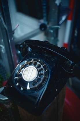 an old black phone sitting on top of a wooden box