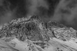 A dramatic monochrome shot of jagged mountain peaks under heavy clouds.