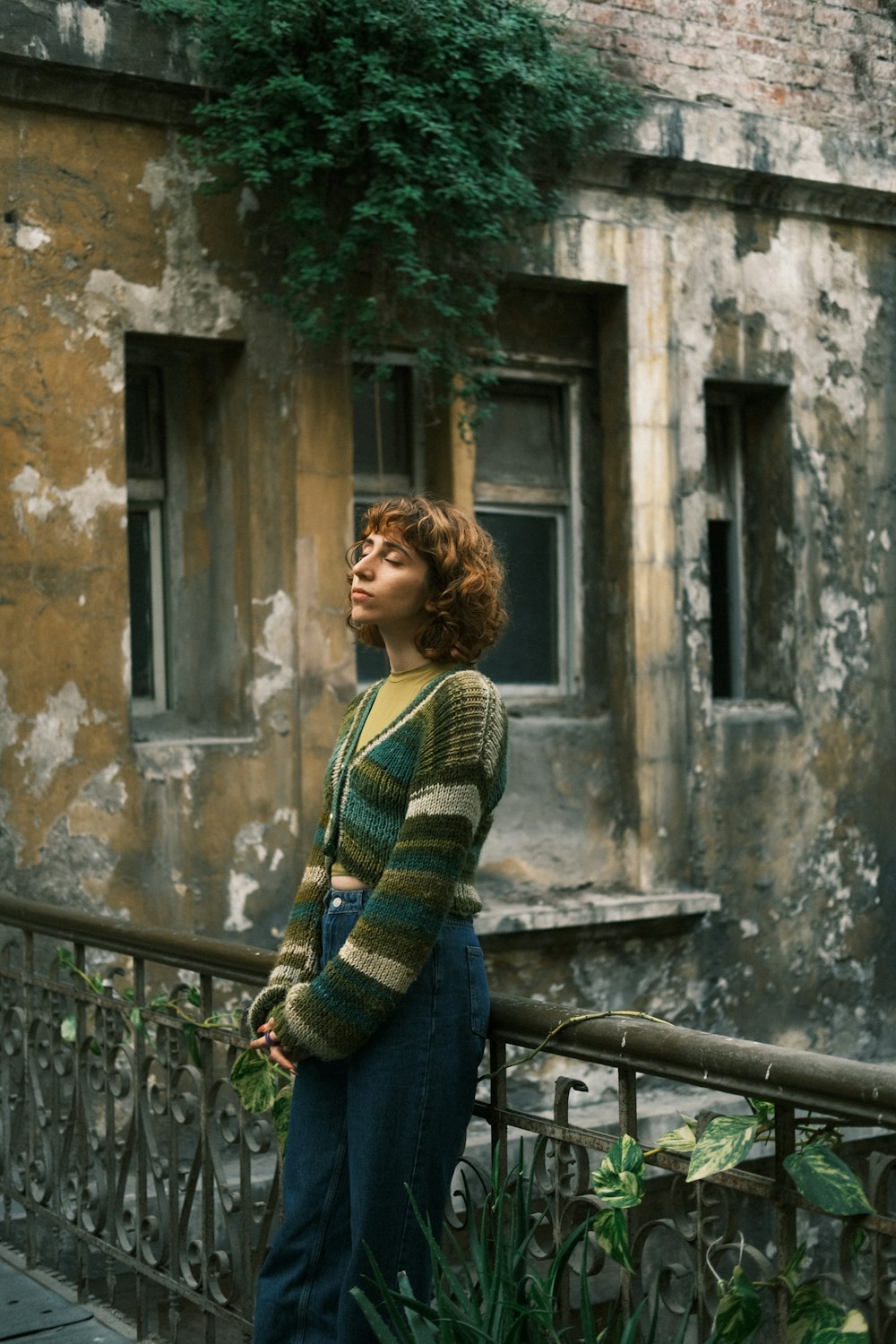 a woman standing on a balcony next to a building