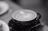 Elegant black and white shot of a steaming cup of coffee on a minimalist table.