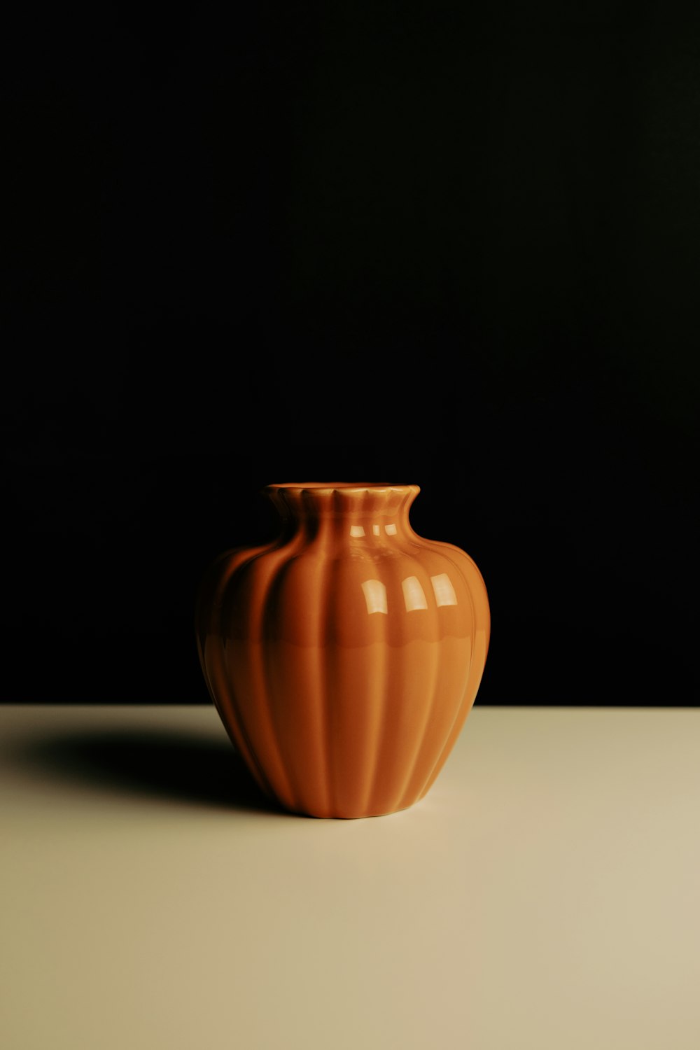 an orange vase sitting on a white table