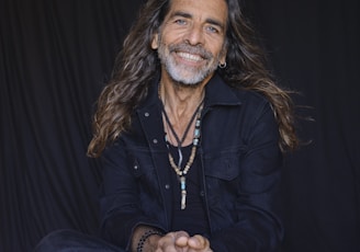 a man with long hair sitting on the ground