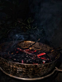 Close-up of golden litti balls resting in a rustic wooden bowl with smoke rising gently.