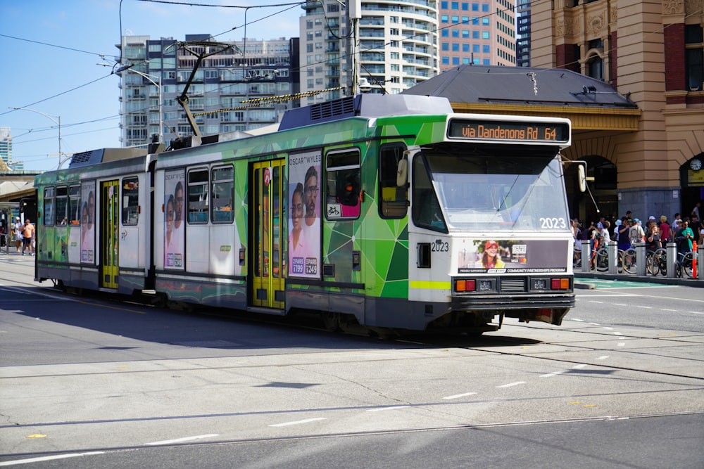 a green and white trolley on a city street