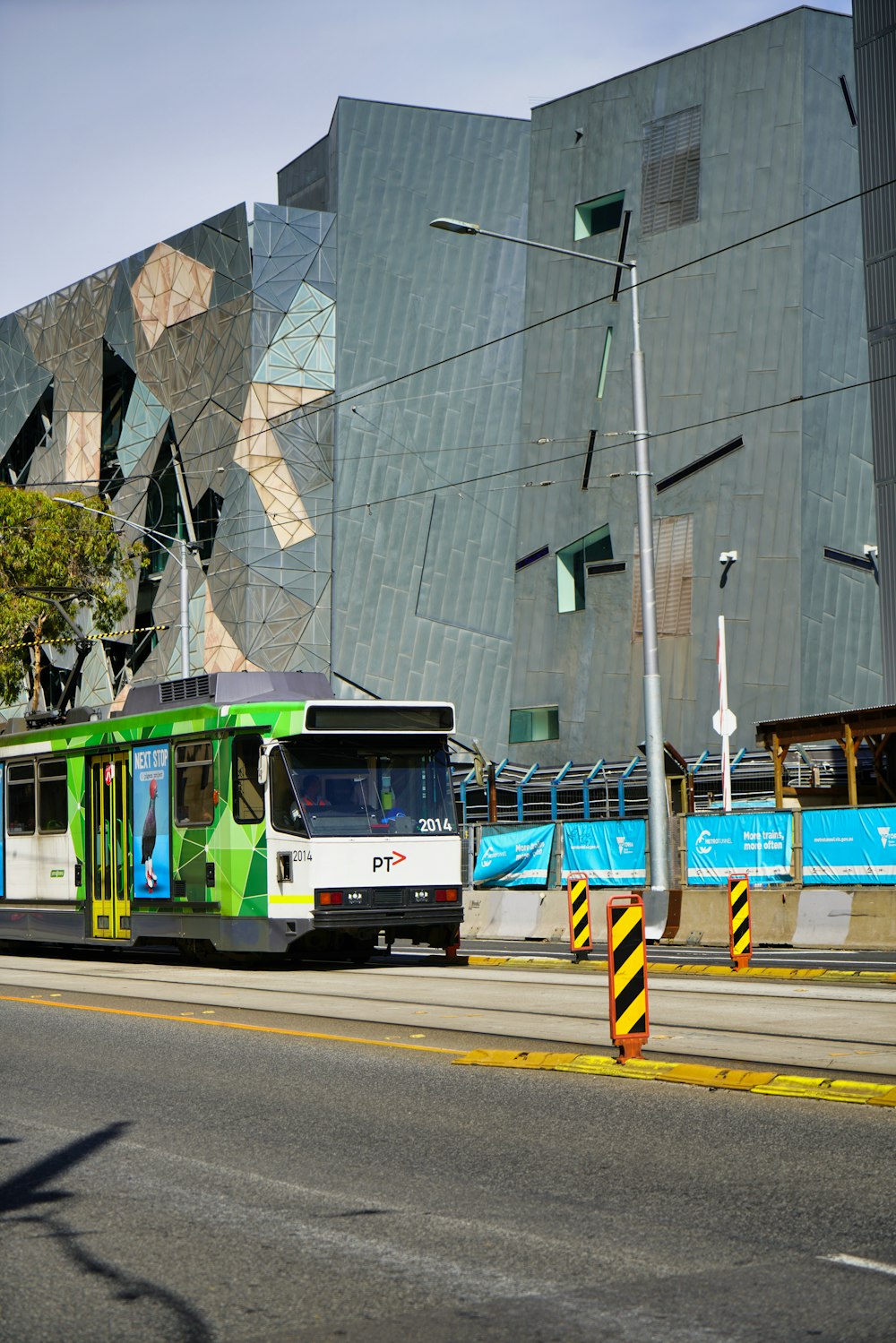 a green and white bus driving down a street next to a tall building