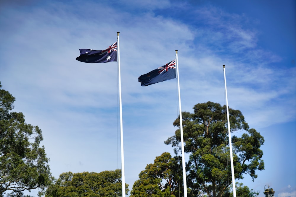 three flags flying in the wind on a sunny day