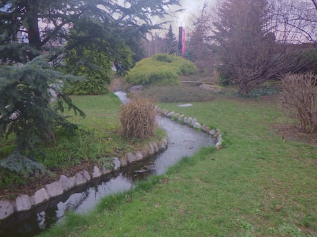 A minimalist dark-mode garden scene featuring a winding, softly illuminated water stream.