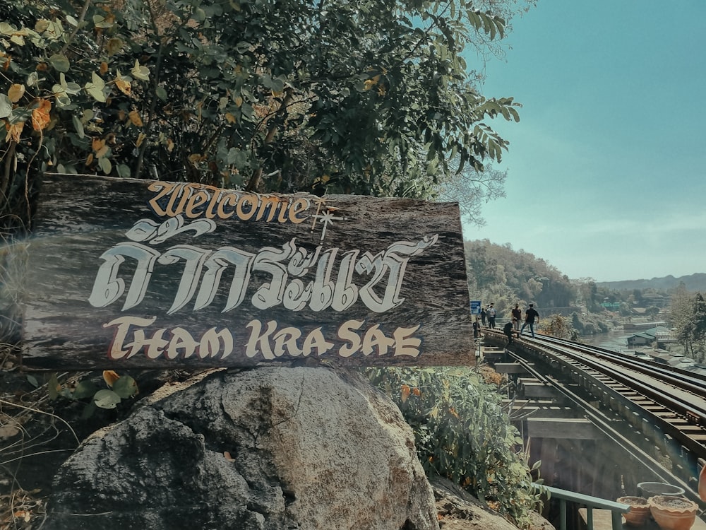 a wooden sign sitting on the side of a train track