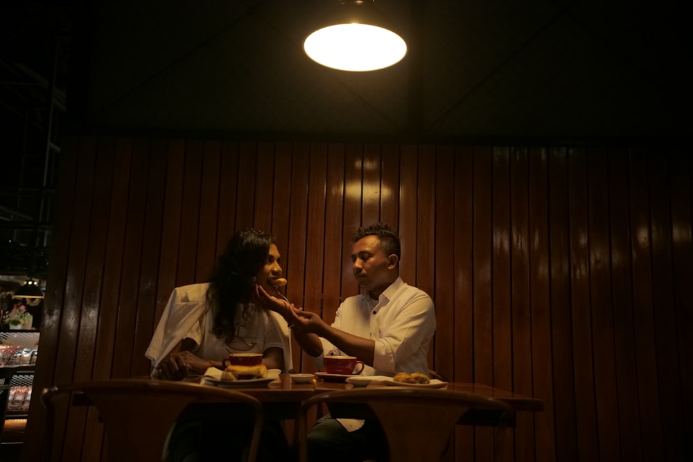 two people sitting at a table in a dark room