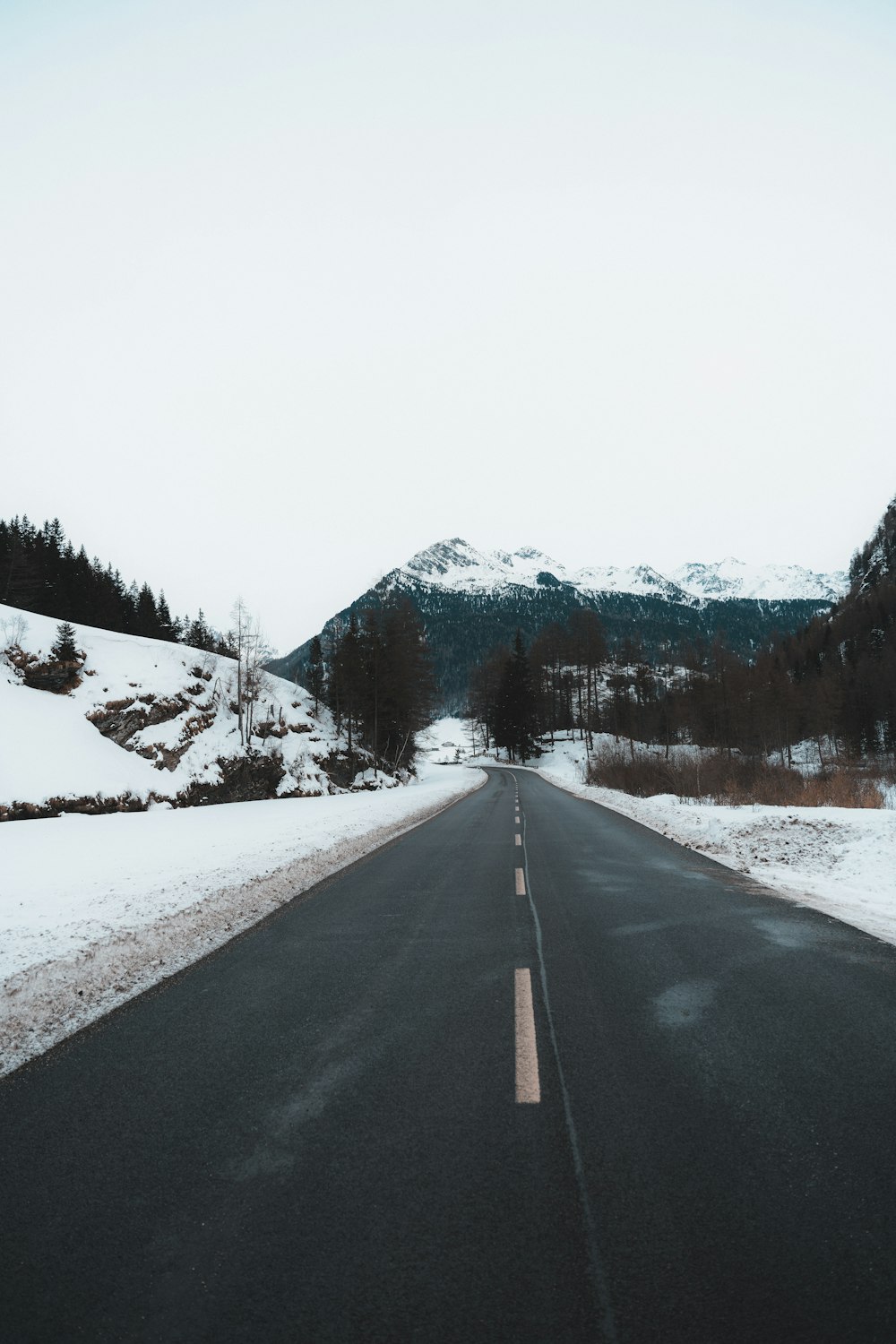 an empty road in the middle of a snowy landscape