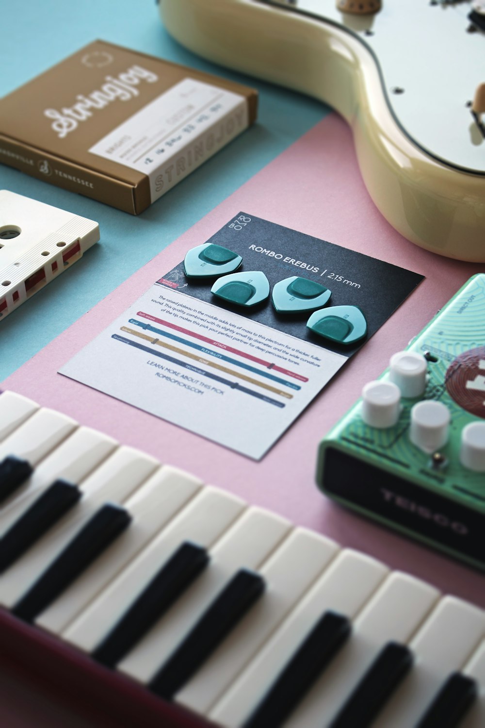 a close up of a keyboard with a guitar in the background