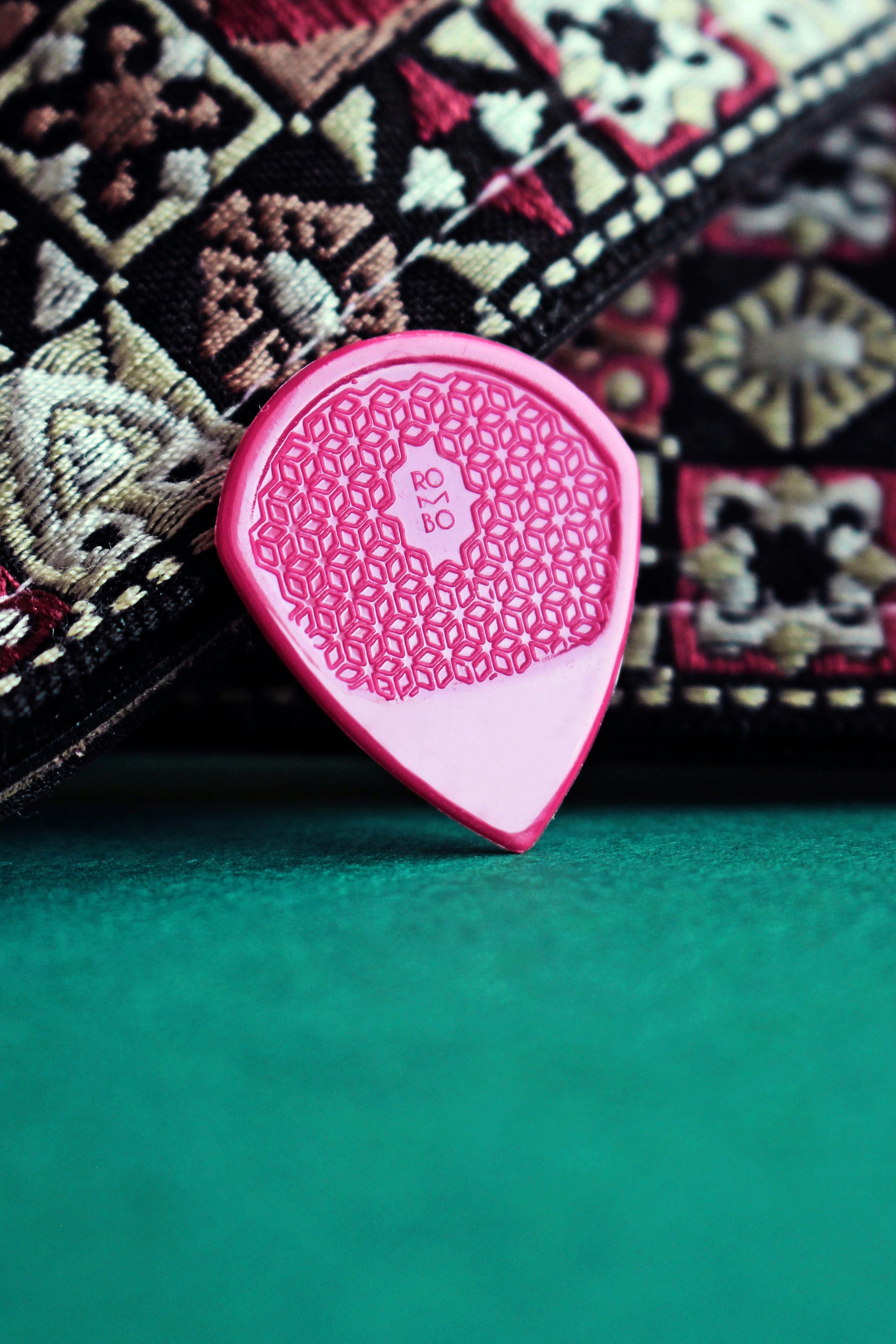 Un médiator de guitare rose posé sur un tapis