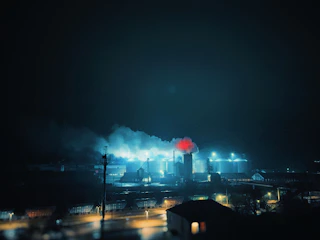 A powerful industrial fire suppression system activating in a heavy refinery environment at dusk.