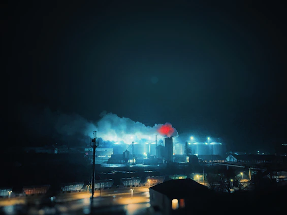A powerful industrial fire suppression system activating in a heavy refinery environment at dusk.