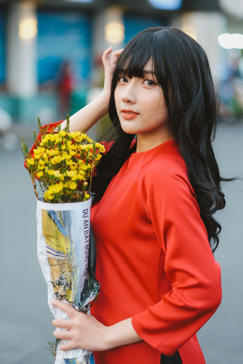 uma mulher em um vestido vermelho segurando um buquê de flores