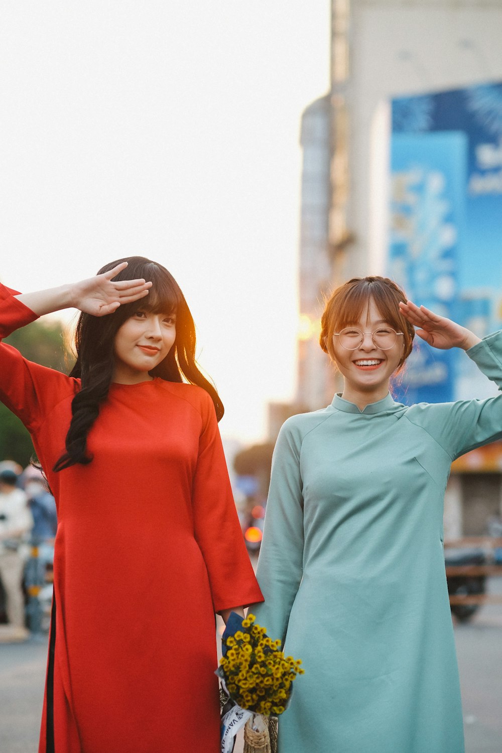 two young women standing next to each other on a street