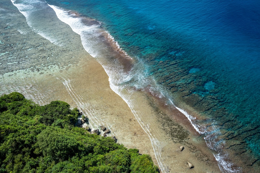 uma vista aérea de uma praia de areia com água azul clara