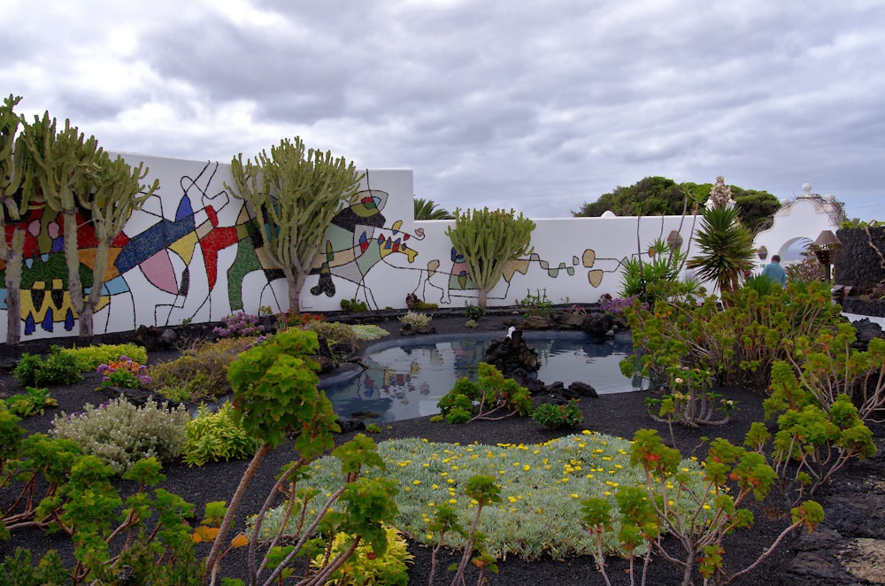 a garden with a mural on the side of a building