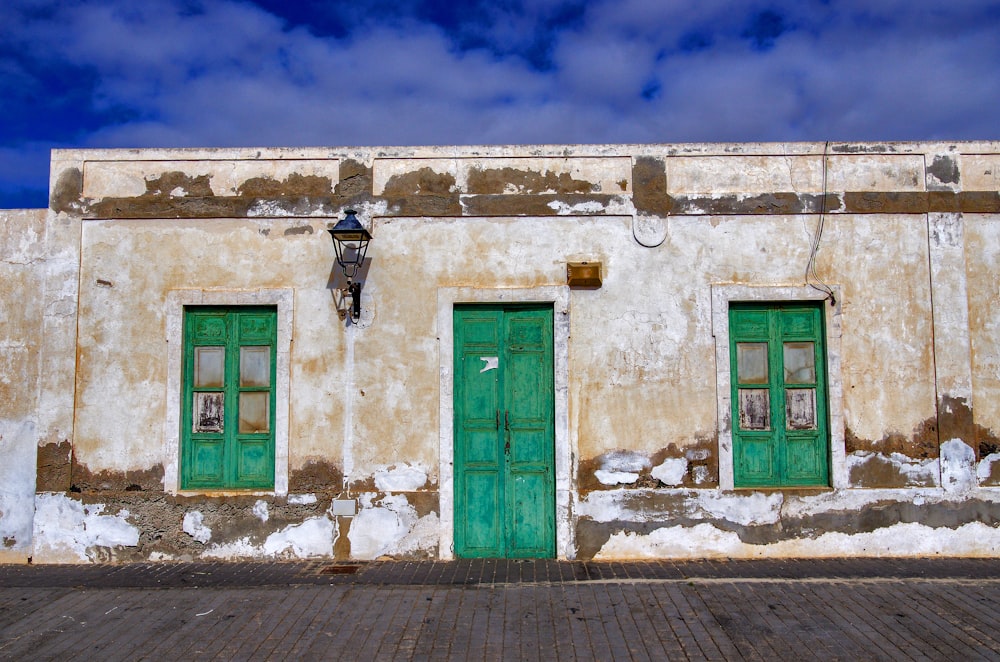 a building with two green doors and a sky background