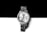 A silver wristwatch with a metallic bracelet is positioned against a contrasting background of black and white. The watch face is adorned with small crystals around the bezel and features three sub-dials. Roman numerals and simple batons mark the hour, and the brand name is printed at the top.