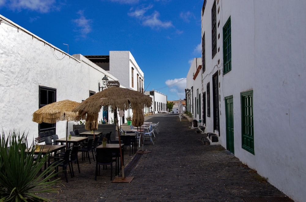 a street lined with tables and umbrellas next to white buildings
