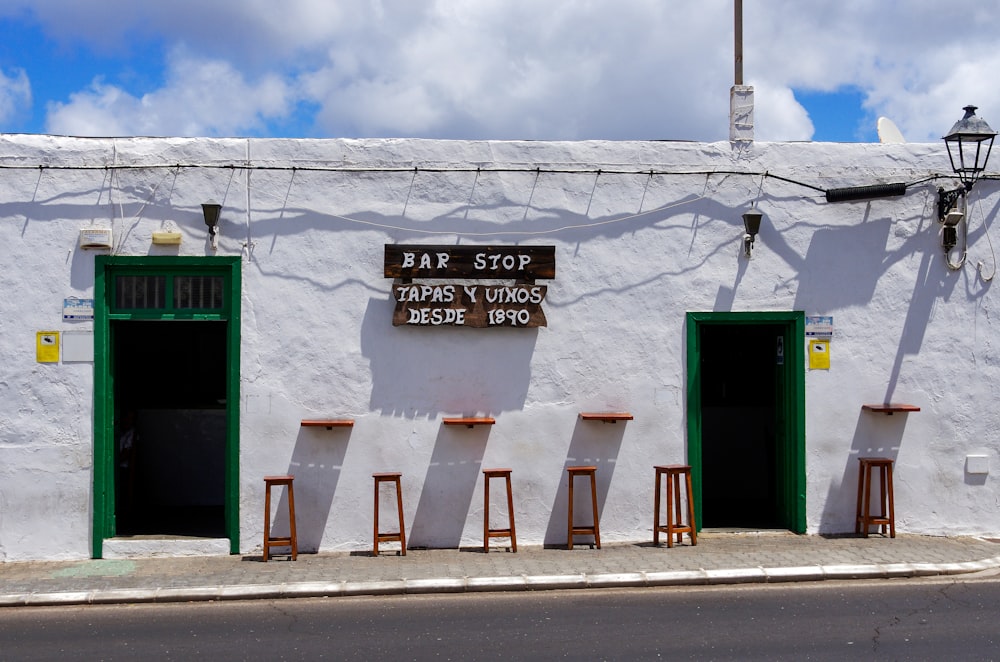 a white building with green doors and a sign that says bar stop