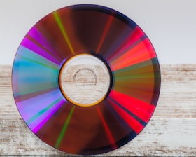 Close-up of stacked compact discs reflecting light on a clean surface.