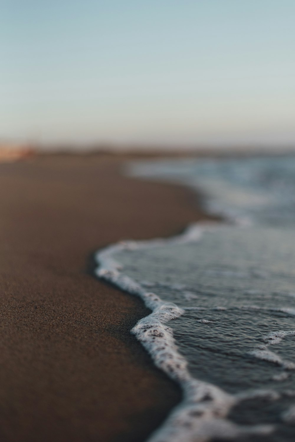 a close up of a beach with waves coming in