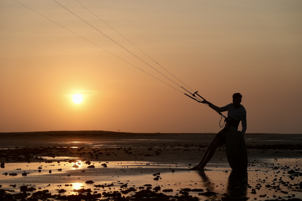 a man standing on a beach flying a kite