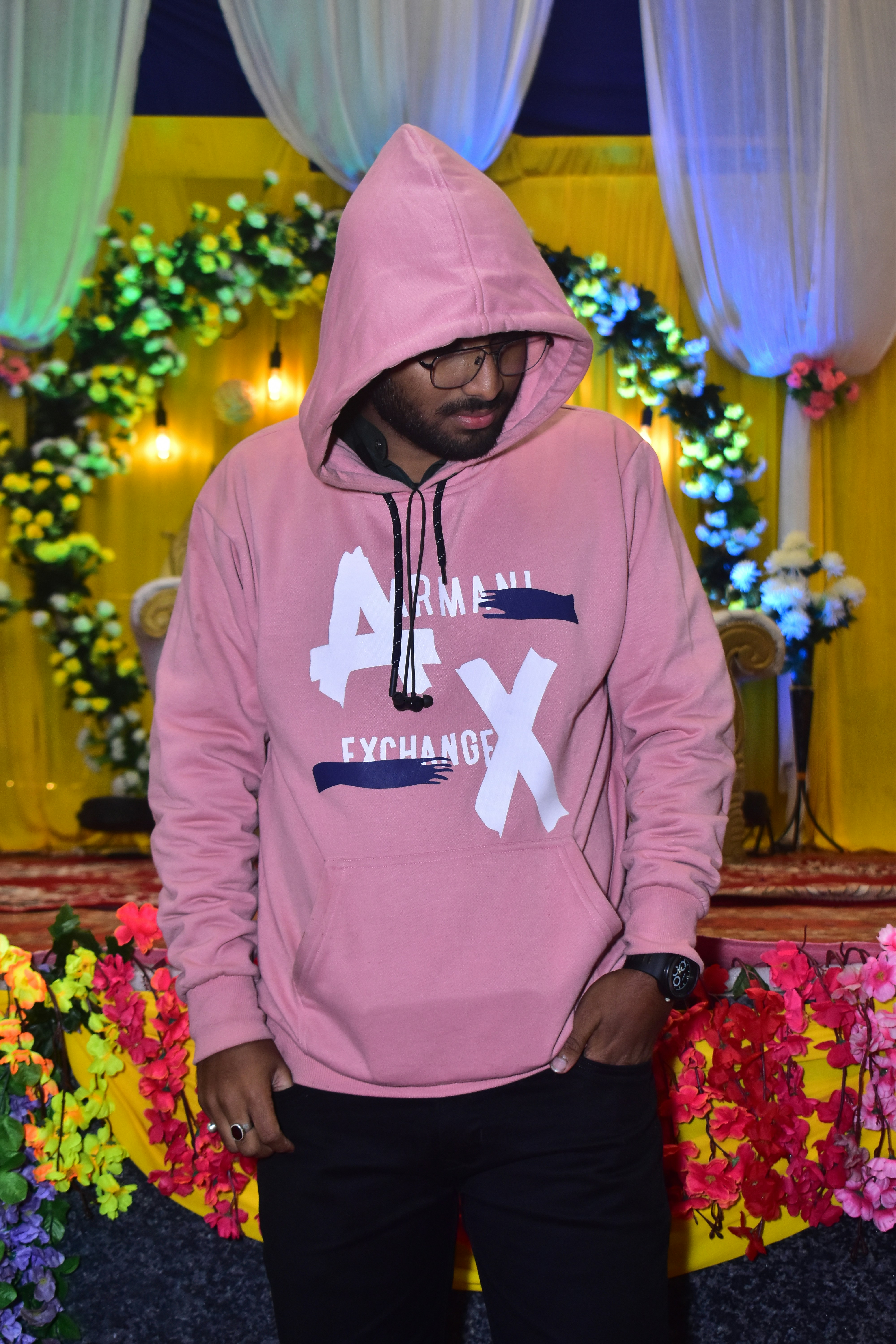 Ein Mann im rosa Kapuzenpulli steht vor einem Blumendisplay