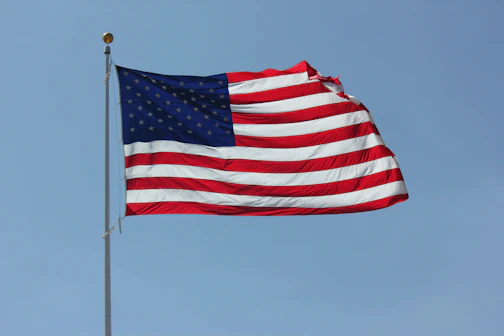 An American flag waving proudly against a clear blue sky.