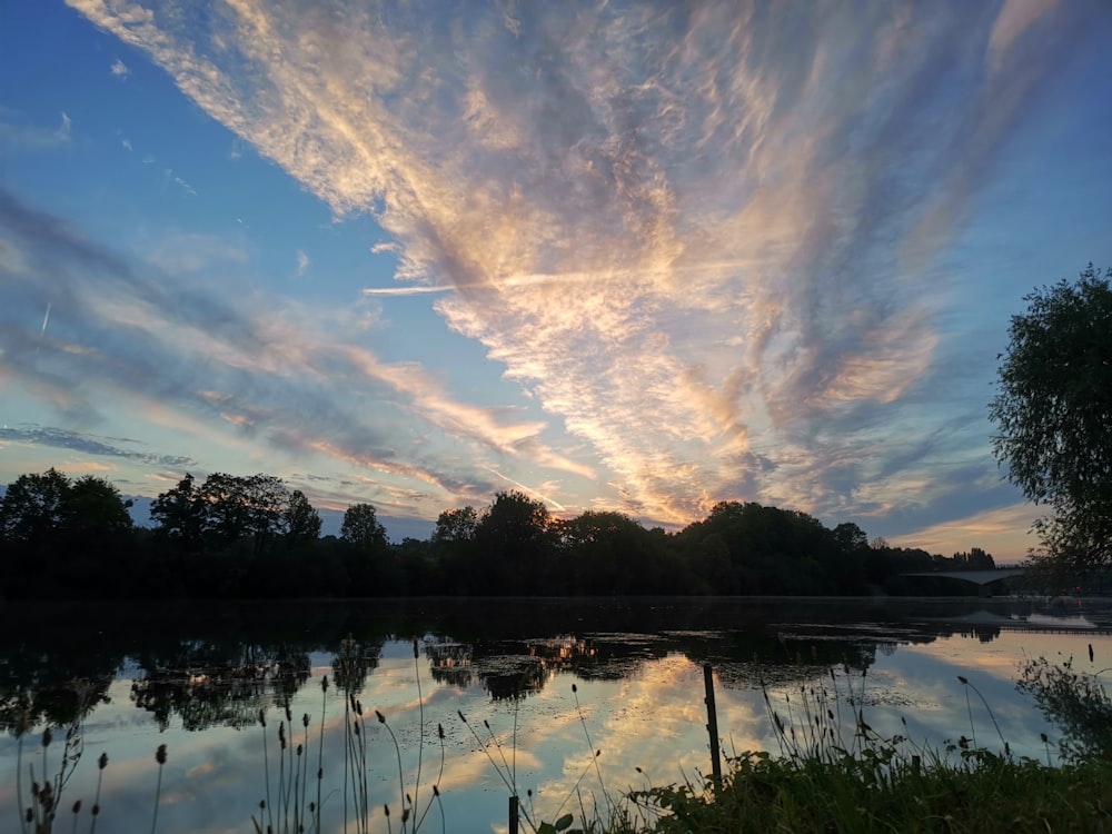 a beautiful sunset over a lake with clouds in the sky