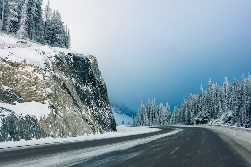 a snow covered mountain road with trees on both sides