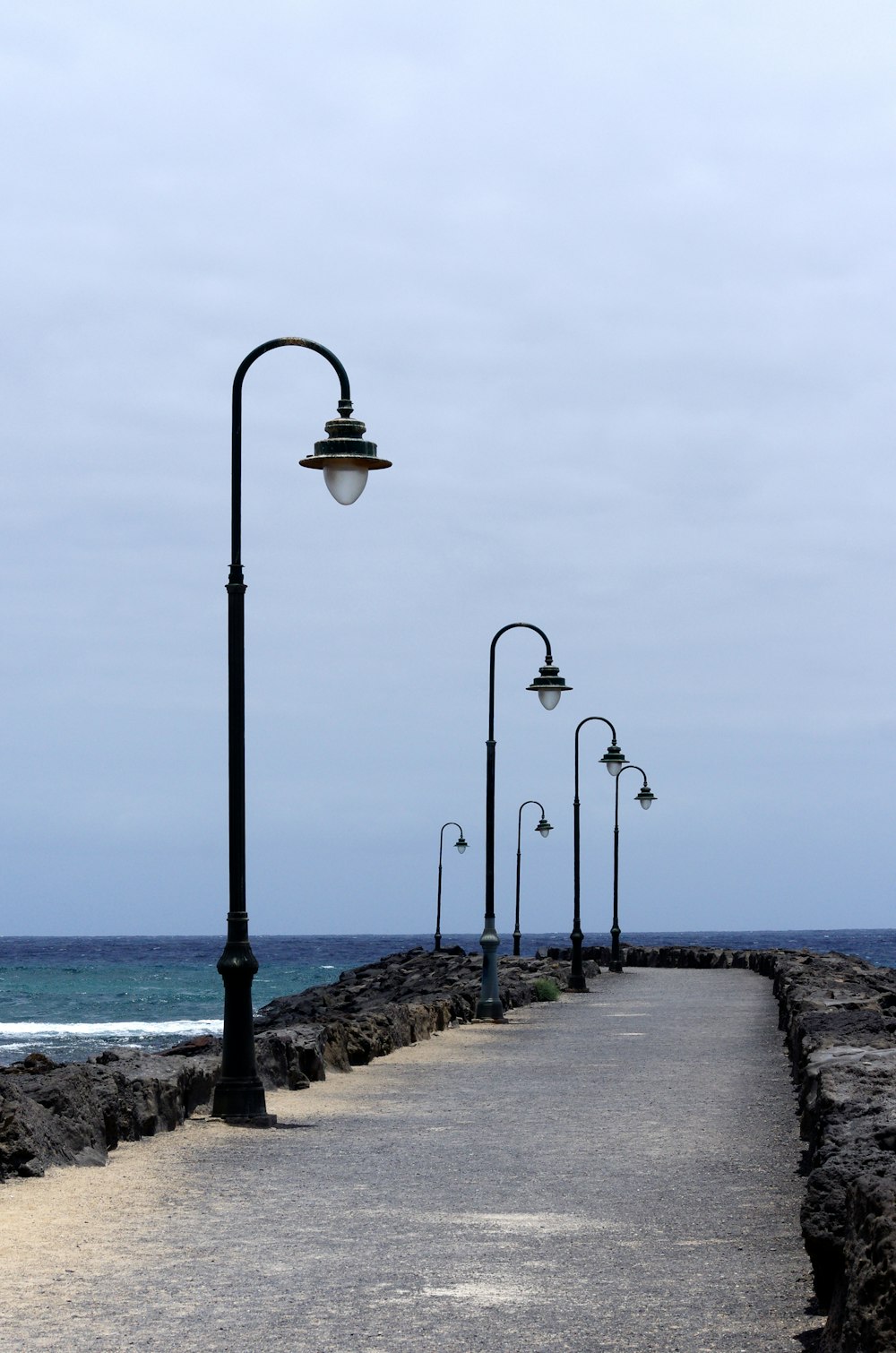a walkway next to the ocean under a cloudy sky