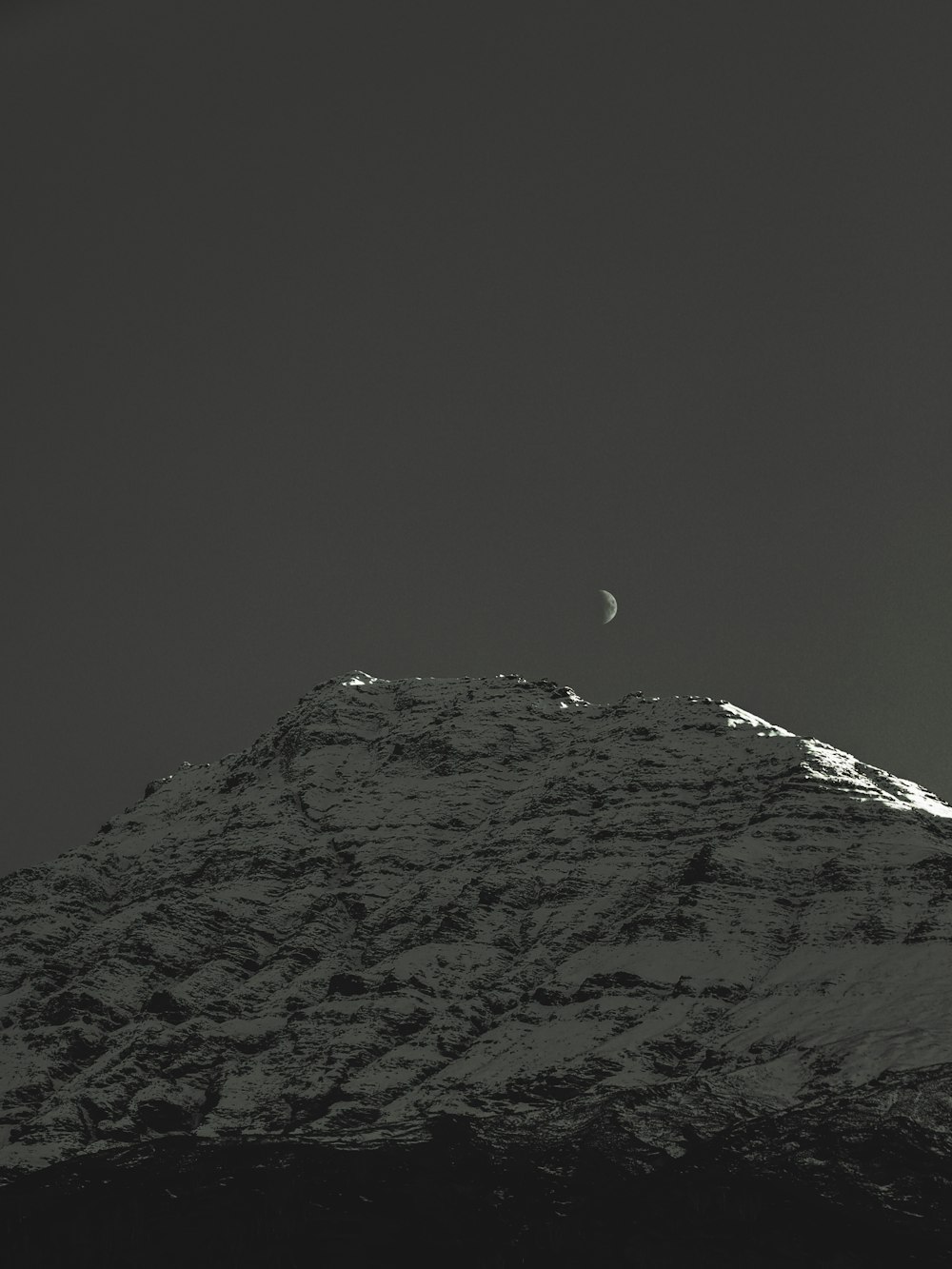 a mountain with a half moon in the sky