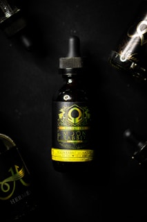 Several dark-colored dropper bottles with elaborate and intricate labels are displayed against a black background. The prominent bottle in the center features a green and yellow design with the text 'Moon Rabbit Signature'. The surrounding bottles are partially visible.