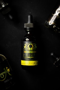 Several dark-colored dropper bottles with elaborate and intricate labels are displayed against a black background. The prominent bottle in the center features a green and yellow design with the text 'Moon Rabbit Signature'. The surrounding bottles are partially visible.