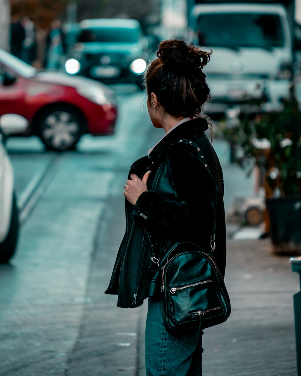 a woman standing on the side of a street holding a purse