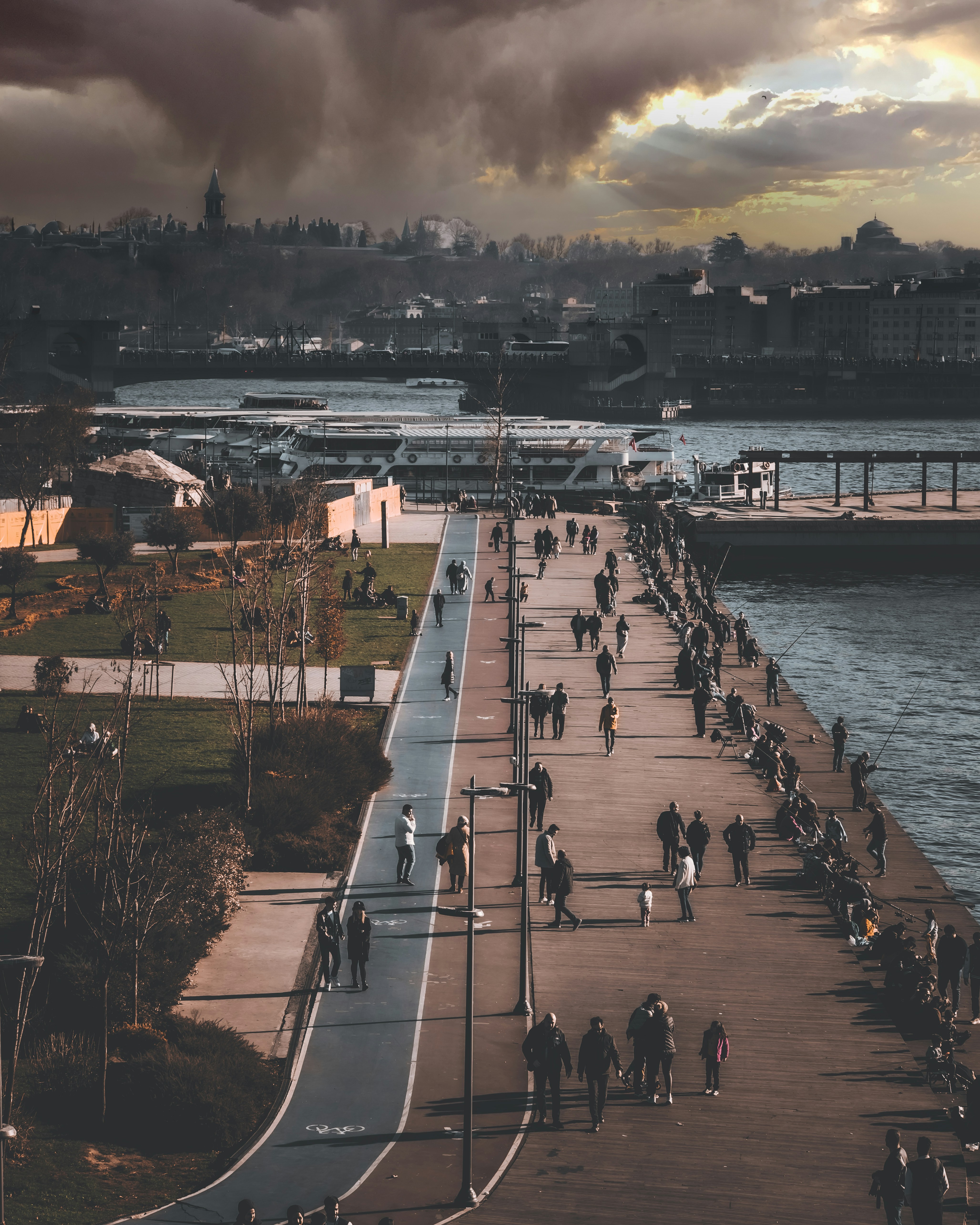 a group of people walking along a walkway next to a body of water