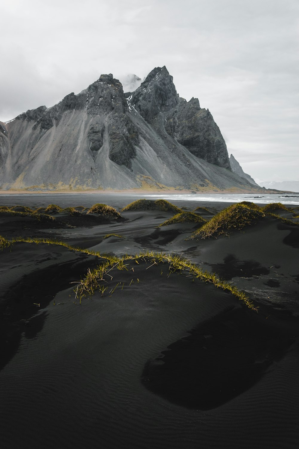 uma praia de areia preta com uma montanha no fundo