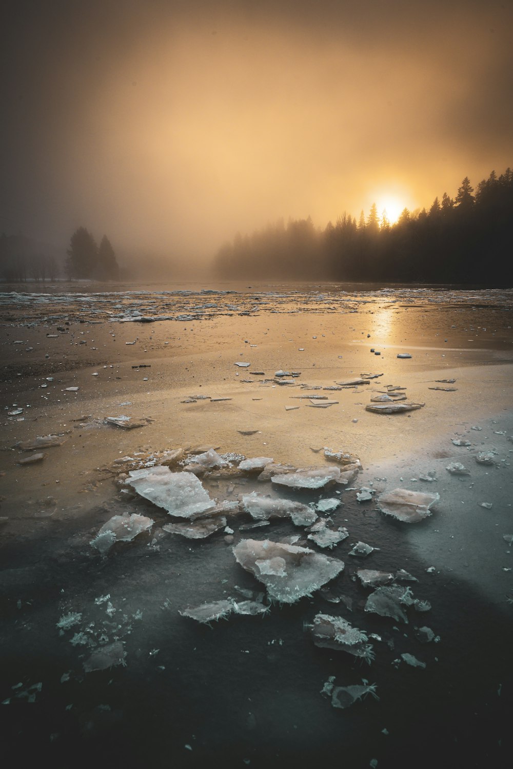 the sun is setting over a frozen lake